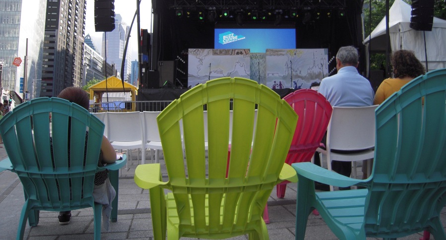 audience sits in brightly colored chairs in front of a sound stage